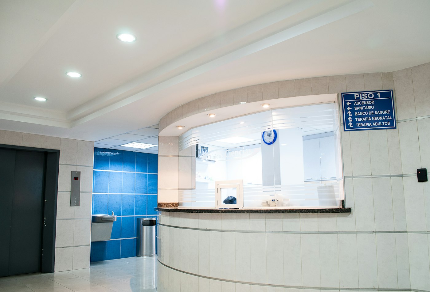 A clinic reception desk and a blue directory sign on the wall